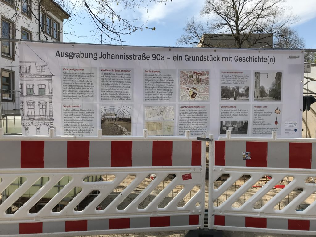Am Bauzaun um das Grundstück Johannisstraße 90a hängt ein großes Banner mit Texten und Bildern zur Geschichte des Grundstücks.